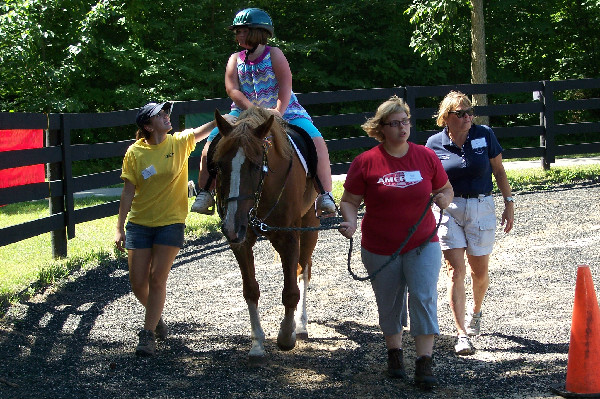 Volunteers assist a rider at Offering Alternative Therapy with Smiles (O.A.T.S.), a PATH International premier accredited center in Clarkston, Michigan.