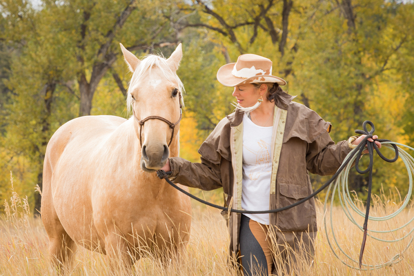 cowgirl with palomino horse in pasture