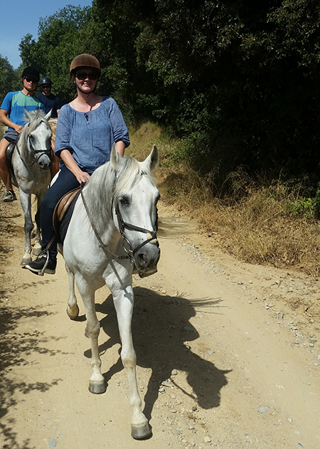 woman riding andalusian horse on trail ride in catalonia spain