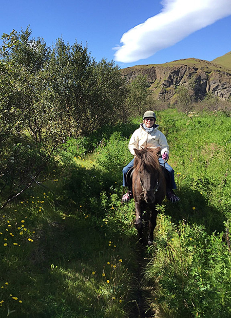 woman riding icelandic horse through trail of flowers