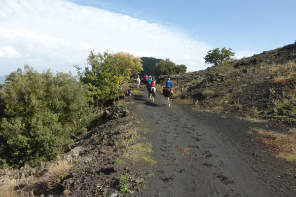 group of equestrians riding along hills in sicily