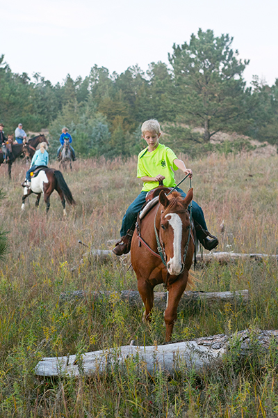 Greg leads his horse over small log obstacles in the Nebraska National Forest