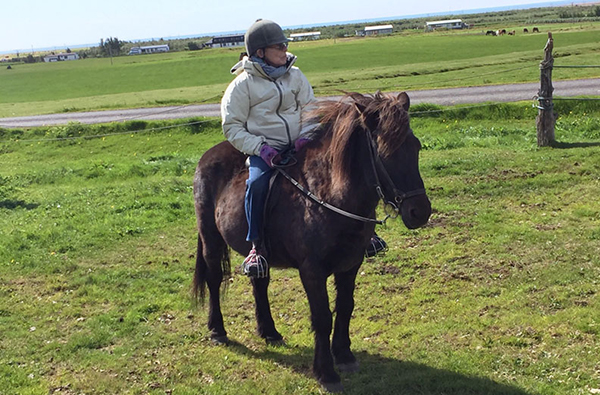 senior woman riding icelandic horse in iceland