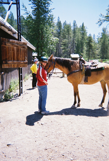 woman and horse prepare for trail ride in glacier national park in montana 